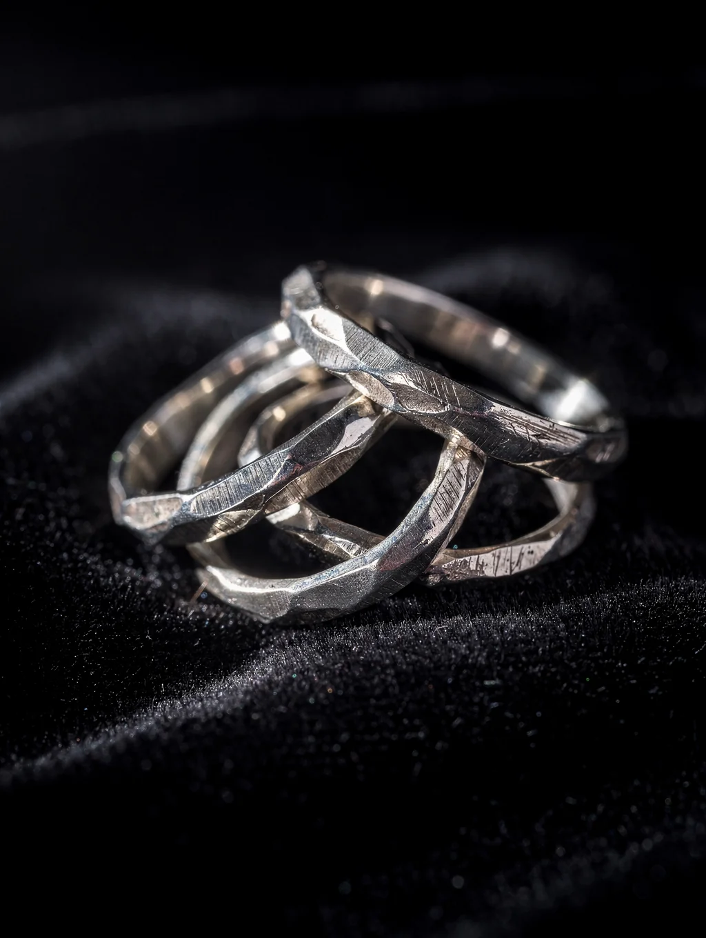 Hand-forged sterling silver rings resting on an artisan slate jeweler bench